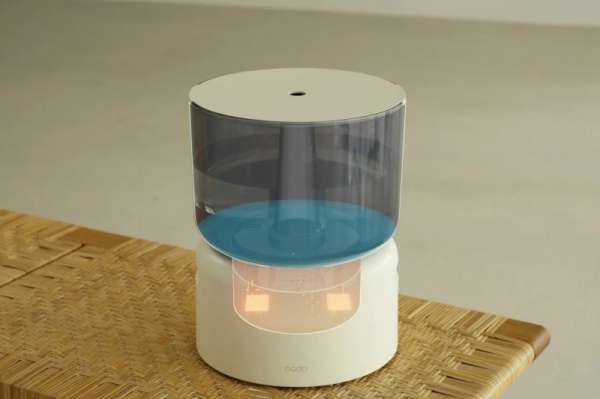 加湿器が置かれた写真です。加湿器は白く、透明な容器に水が入っています。加湿器は木製のテーブルの上に置かれています。