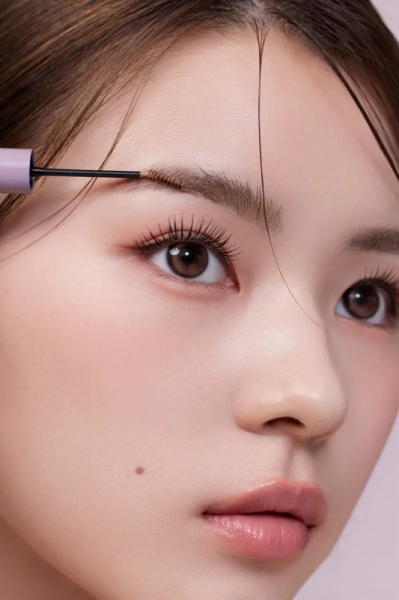 眉毛にブラシをあてている女性の顔のアップ。