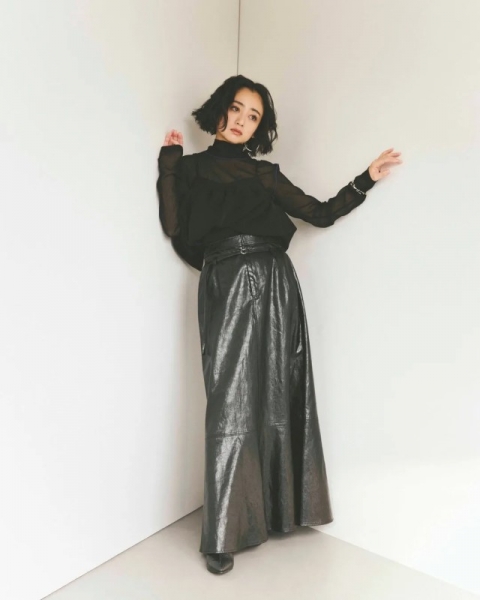 白い壁の角に寄りかかる女性のスタイリング